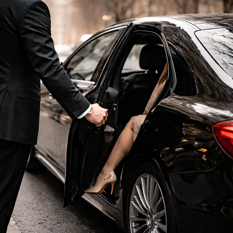 Professional chauffeur opening door for NYC Fashion Week car service client