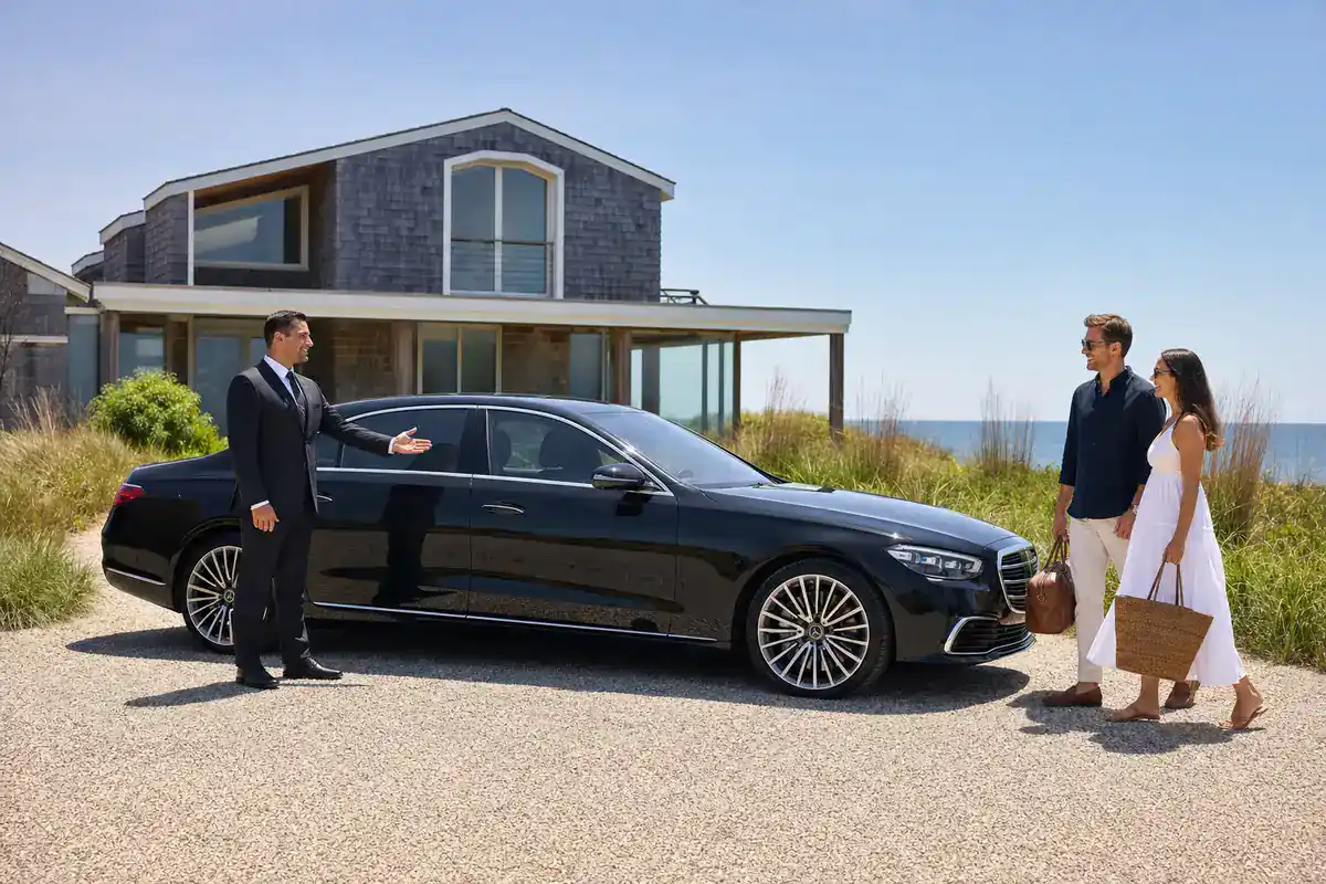 Chauffeur opening the door of a black car for guests arriving at a Hamptons beach house