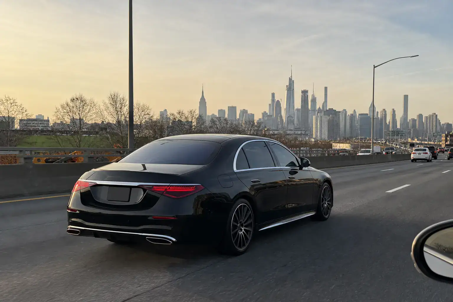 10 Things to Know Before Flying Into JFK Airport (2026) 4 Black Mercedes-Benz S-Class on the expressway heading toward the Manhattan skyline
