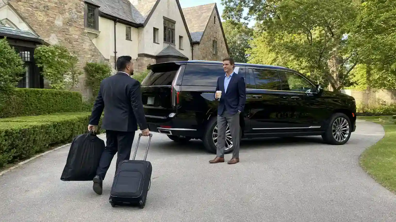 Chauffeur loading luggage into a black SUV outside a Westchester home for an airport transfer