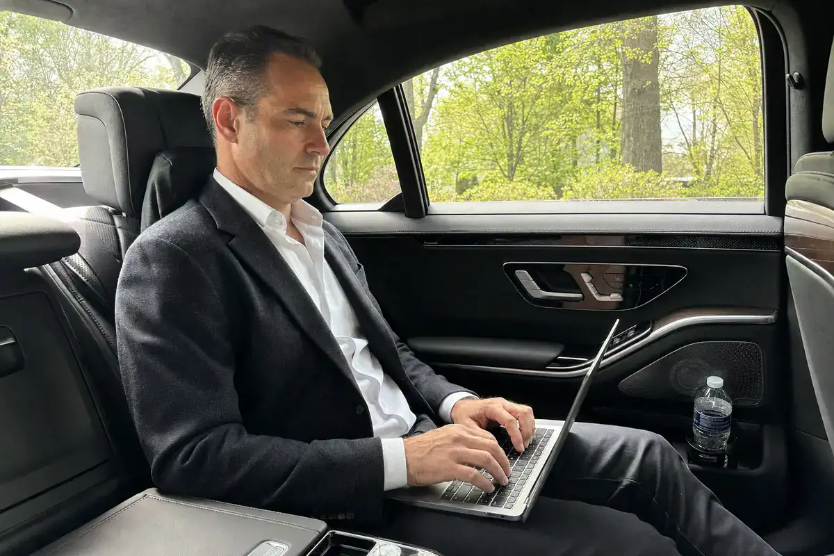 Business traveler working on a laptop in the back of a luxury car from Harrison