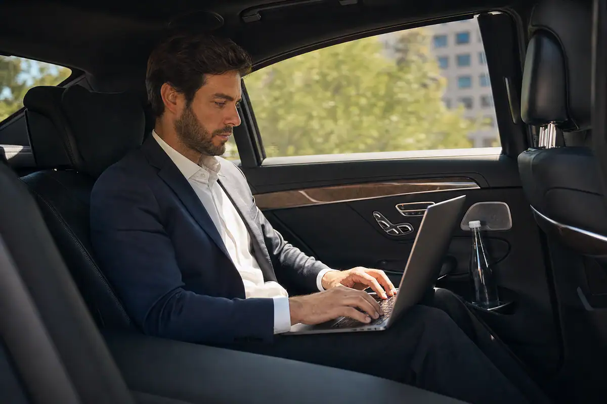 Business traveler working on a laptop in the back of a luxury car from White Plains