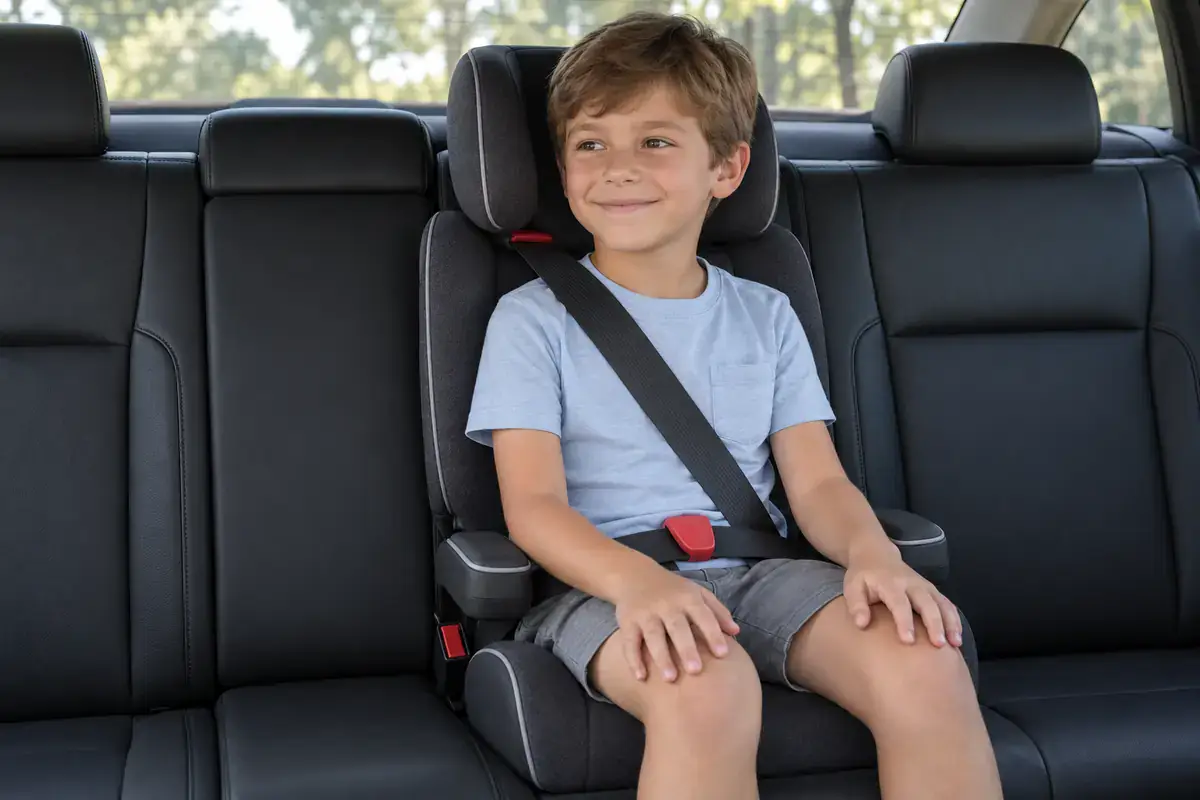 Child in a high-back booster seat with the seat belt across the chest in a black sedan in NYC