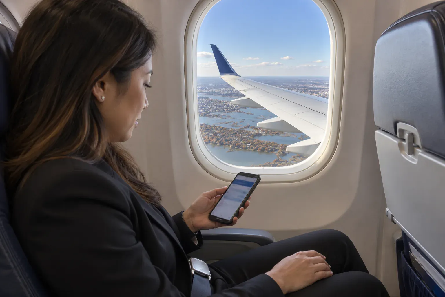 10 Things to Know Before Flying into JFK Airport (2026) 2 Traveler checking her arrival terminal on her phone before landing at JFK