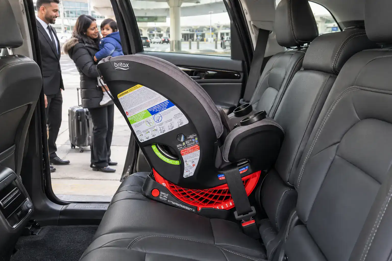 Child car seat installed in a Lincoln Nautilus as a mother and toddler wait at the Newark Airport curb