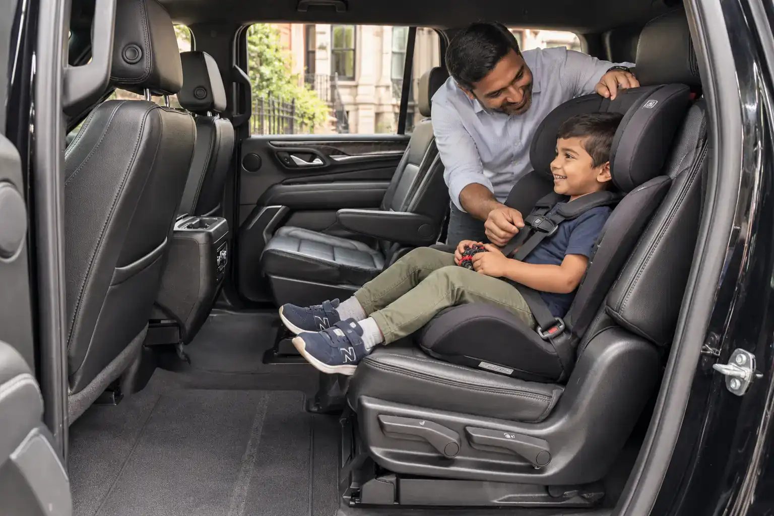 Parent checking the harness on a convertible car seat in a black SUV before a car service ride in NYC