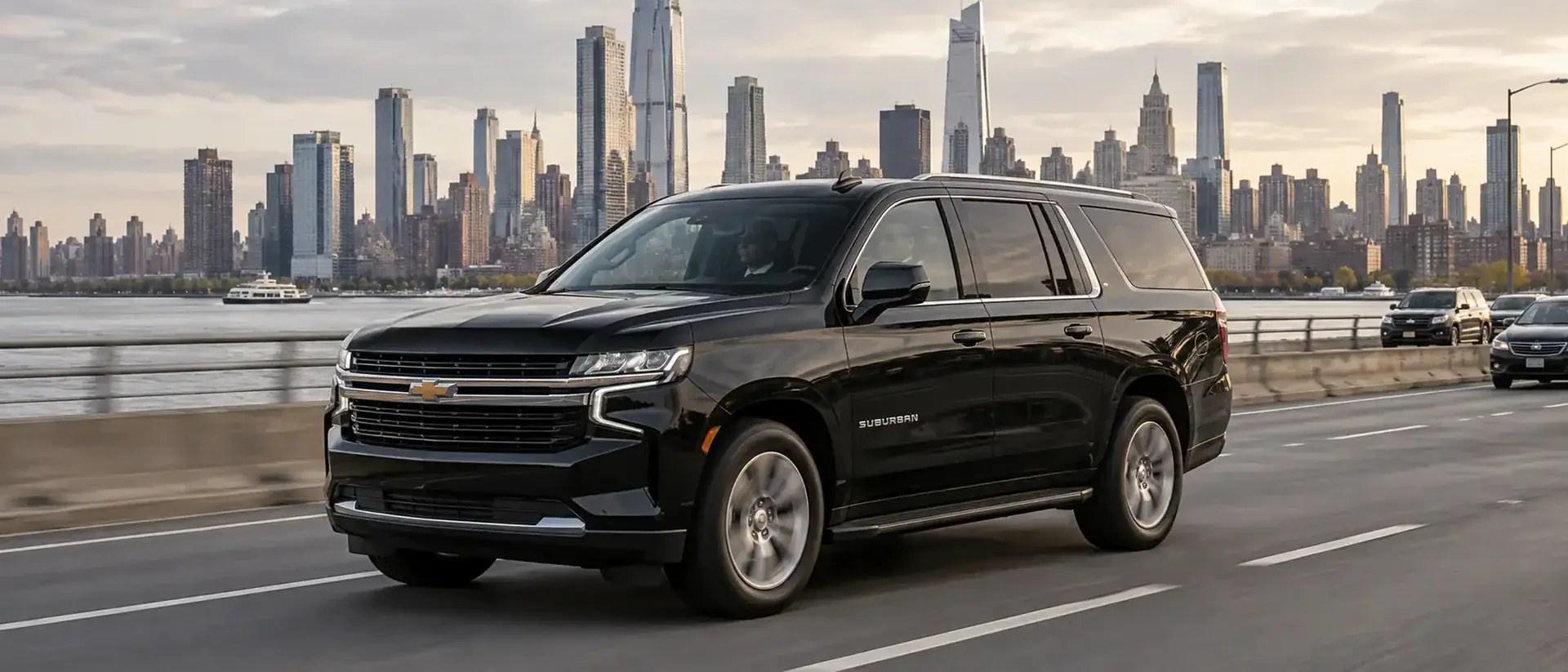 Black chauffeured SUV driving along the Hudson River with the Manhattan skyline behind it