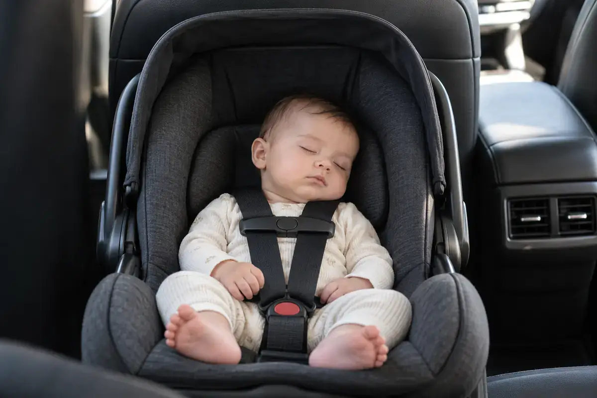 Baby asleep in a rear-facing infant car seat in the back of a black car service vehicle in NYC